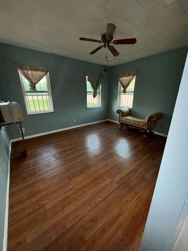 unfurnished room with ceiling fan, dark wood-style flooring, and baseboards