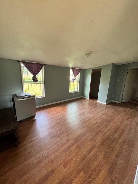 unfurnished living room with wood finished floors and baseboards