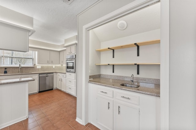 kitchen with open shelves, white cabinetry, stainless steel appliances, and a sink