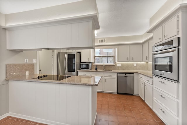 kitchen featuring a peninsula, appliances with stainless steel finishes, visible vents, and white cabinets