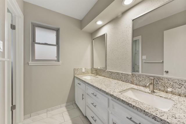 bathroom featuring double vanity, marble finish floor, baseboards, and a sink