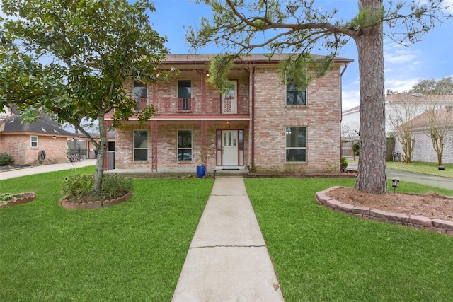 traditional-style home with a balcony, a front yard, a porch, and brick siding