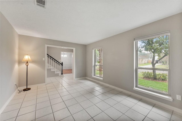 spare room with stairs, visible vents, baseboards, and light tile patterned floors