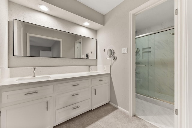 bathroom with double vanity, a sink, a marble finish shower, and baseboards