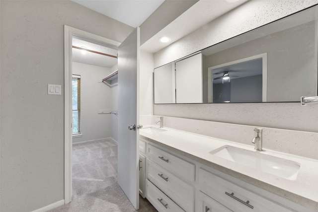 bathroom featuring a sink, a spacious closet, baseboards, and double vanity