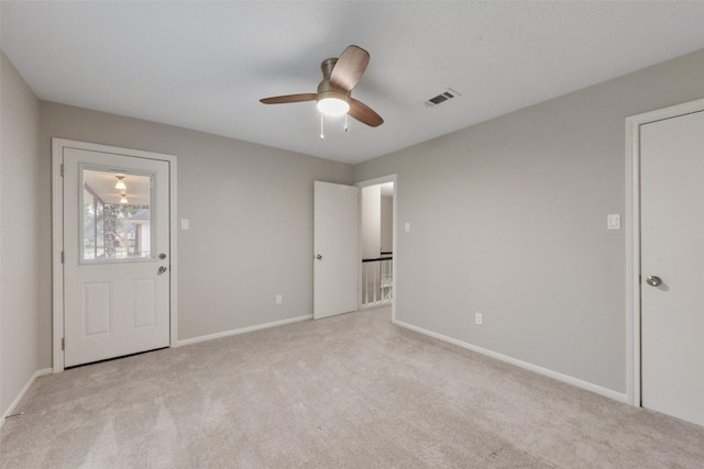 spare room with baseboards, visible vents, ceiling fan, and light colored carpet