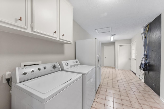 laundry room with light tile patterned floors, a textured ceiling, washer and dryer, cabinet space, and attic access