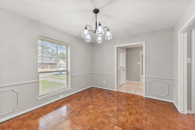 unfurnished room featuring wainscoting, a notable chandelier, and a textured ceiling