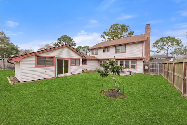 rear view of house with a fenced backyard, a yard, and a chimney