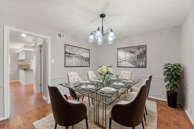 dining space with a chandelier, a wainscoted wall, and visible vents