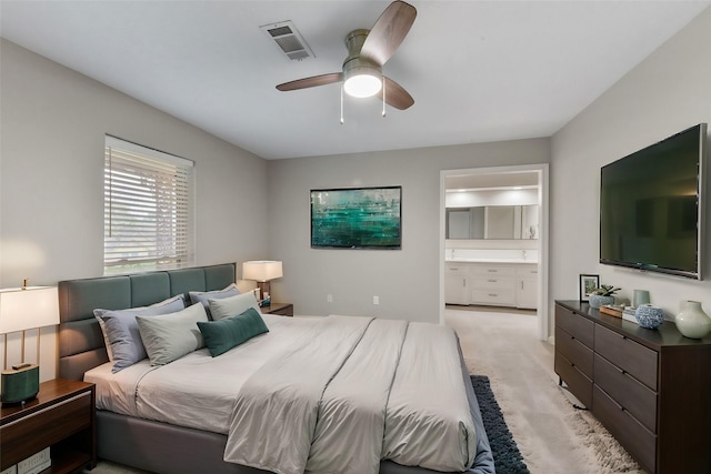 bedroom featuring ceiling fan, connected bathroom, visible vents, and light colored carpet