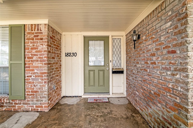 view of exterior entry featuring a porch and brick siding