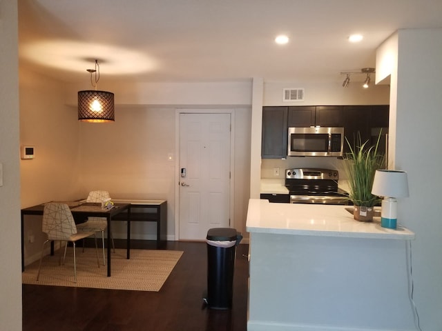 kitchen with dark wood-style flooring, light countertops, hanging light fixtures, visible vents, and appliances with stainless steel finishes