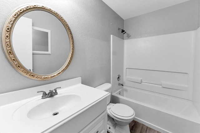 bathroom with a textured wall, bathtub / shower combination, toilet, wood finished floors, and vanity