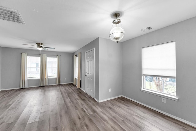 spare room with light wood finished floors, plenty of natural light, and visible vents