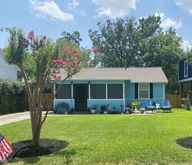 view of front of house featuring a shingled roof, a front yard, and concrete driveway