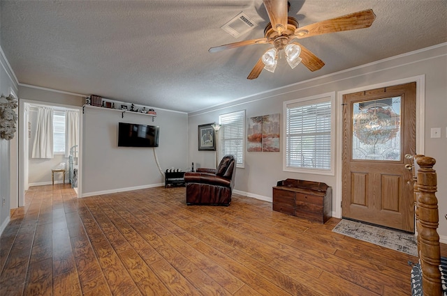 foyer featuring a textured ceiling, wood finished floors, visible vents, and crown molding