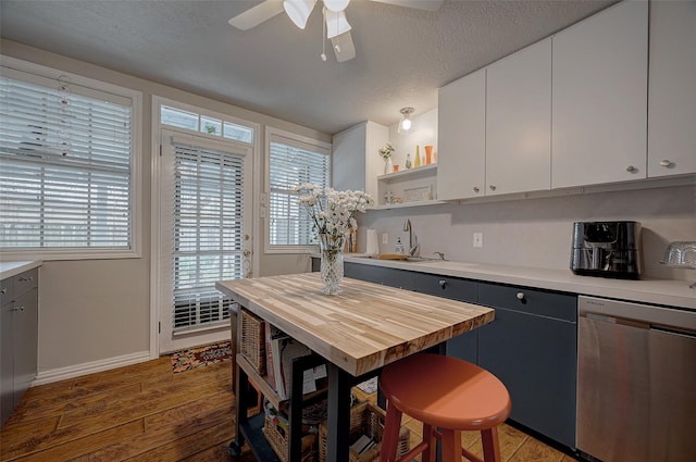 kitchen with a textured ceiling, light wood-style floors, white cabinets, stainless steel dishwasher, and open shelves