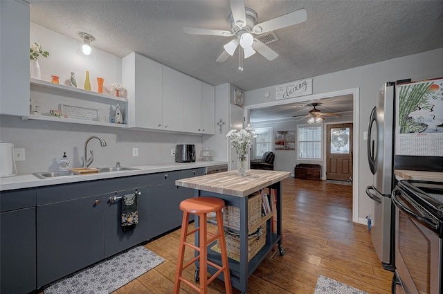 kitchen featuring open shelves, light countertops, appliances with stainless steel finishes, white cabinets, and a sink