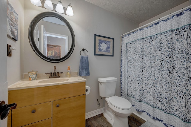 full bath with toilet, vanity, a textured ceiling, wood finished floors, and baseboards