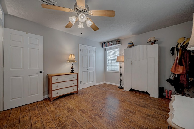 bedroom featuring dark wood-style floors, ceiling fan, baseboards, and a textured ceiling