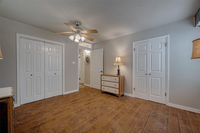 unfurnished bedroom with a ceiling fan, a textured ceiling, baseboards, and wood finished floors