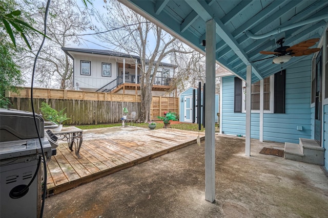 view of patio with a ceiling fan, a fenced backyard, an outbuilding, a deck, and a shed