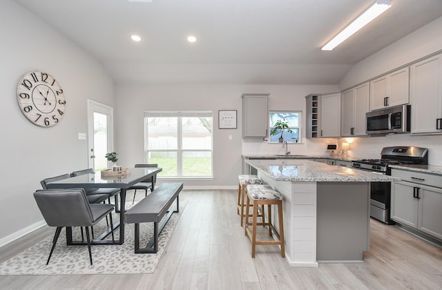 915 Acorn Trail Pl, Tomball, TX 77375 - kitchen featuring stainless steel appliances, gray cabinets, lofted ceiling, a center island, and light wood-style floors