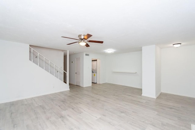 unfurnished living room featuring light wood-style flooring, stairway, ceiling fan, washer / dryer, and baseboards