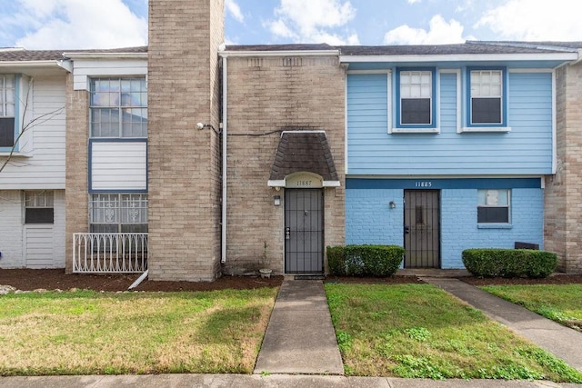 townhome / multi-family property featuring brick siding and a front lawn