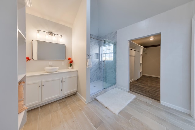 full bathroom with baseboards, vanity, wood tiled floor, and a shower stall