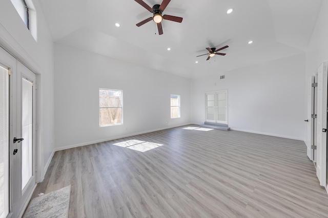 unfurnished living room featuring baseboards, a high ceiling, recessed lighting, french doors, and light wood-style floors