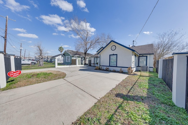 bungalow-style home with a fenced front yard, a front yard, driveway, and stucco siding