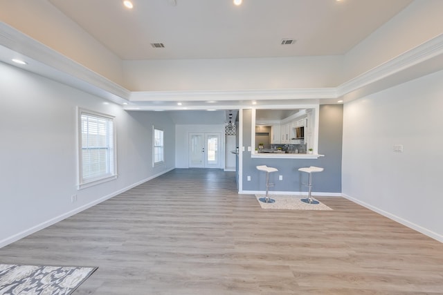 unfurnished living room featuring visible vents, light wood-style flooring, and baseboards