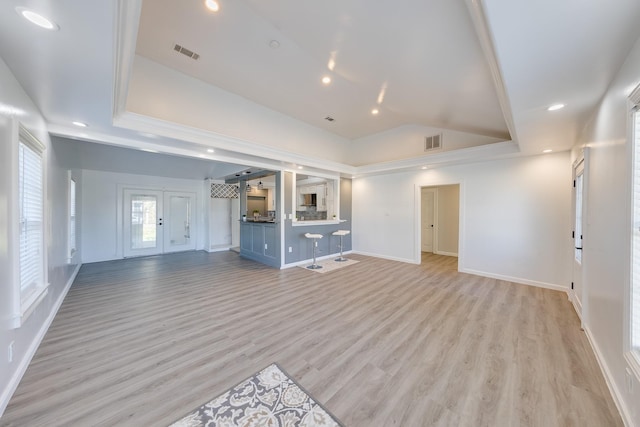 unfurnished living room with a tray ceiling, visible vents, and light wood-style flooring