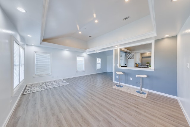 unfurnished living room with visible vents, baseboards, light wood-type flooring, a tray ceiling, and recessed lighting