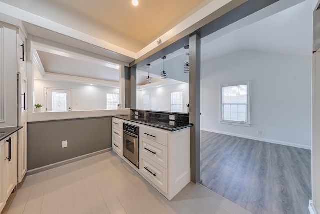 kitchen with oven, a healthy amount of sunlight, and light wood-style flooring