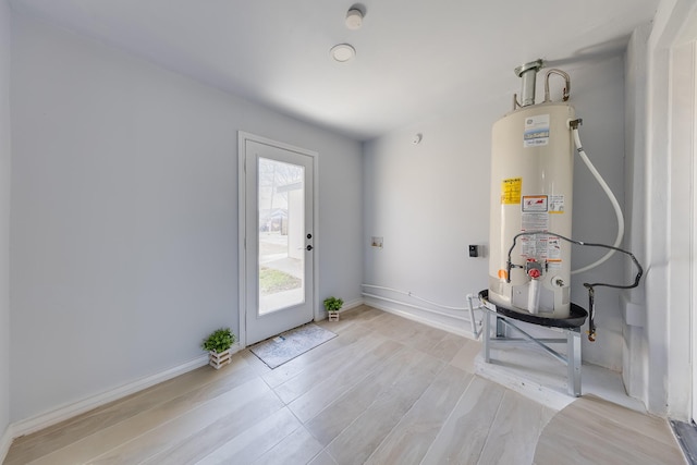 entryway with water heater, light wood-type flooring, and baseboards