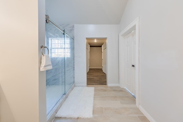 bathroom with a marble finish shower, a walk in closet, and baseboards