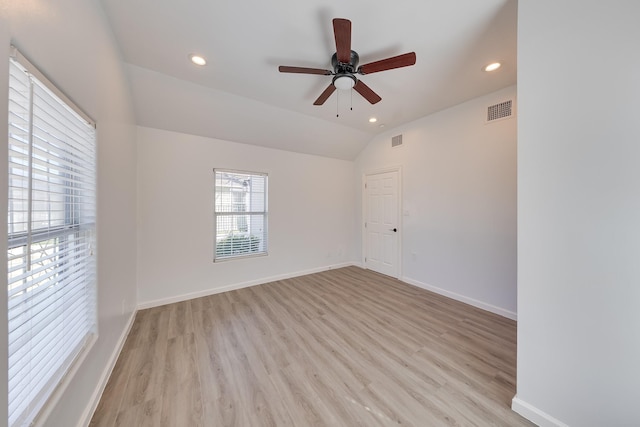 empty room featuring lofted ceiling, light wood-style floors, visible vents, and baseboards