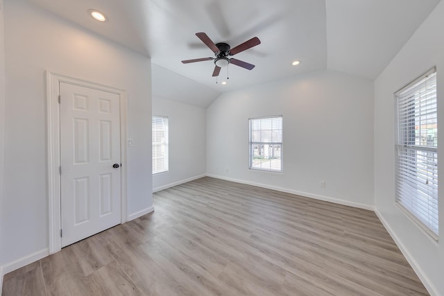 empty room with lofted ceiling, recessed lighting, light wood-style flooring, and baseboards