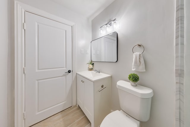 bathroom with toilet, vanity, and wood finished floors