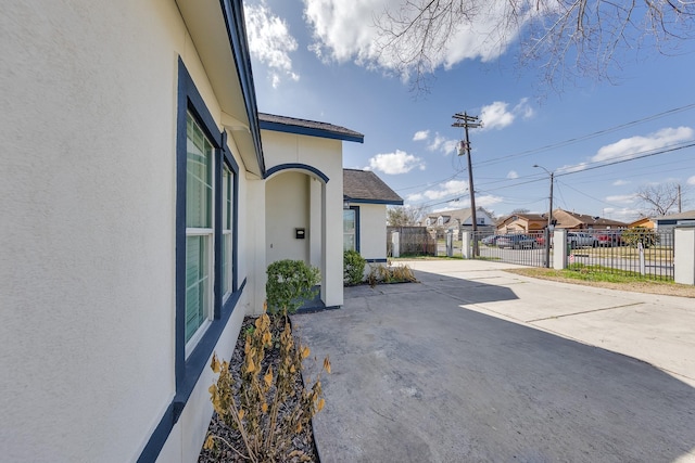 view of patio featuring fence, a residential view, and driveway