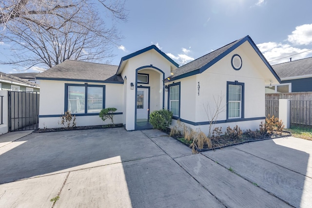 view of front of home with a shingled roof, fence, and stucco siding