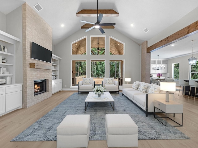 living area featuring light wood finished floors, a fireplace, visible vents, and beam ceiling