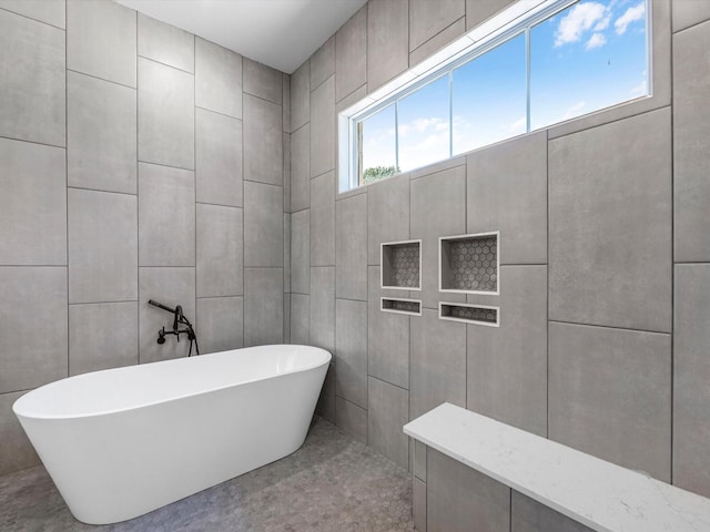 full bathroom with a soaking tub and tile walls