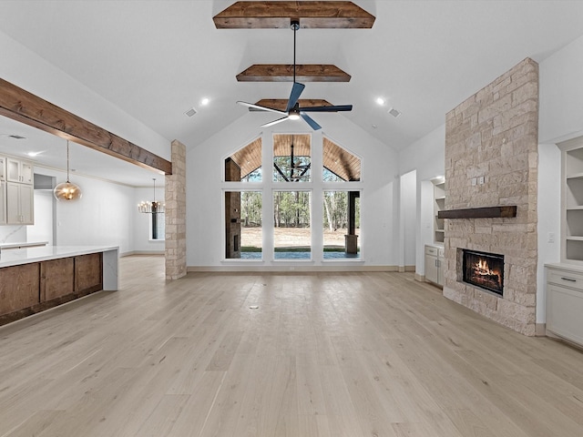 15681 Connie Ln, Montgomery, TX 77316 - unfurnished living room featuring beamed ceiling, built in shelves, ceiling fan with notable chandelier, light wood-style floors, and a fireplace