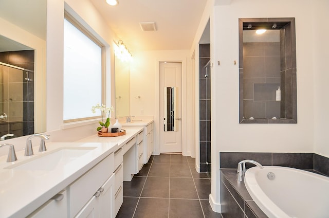 bathroom with double vanity, a garden tub, a sink, and tile patterned floors