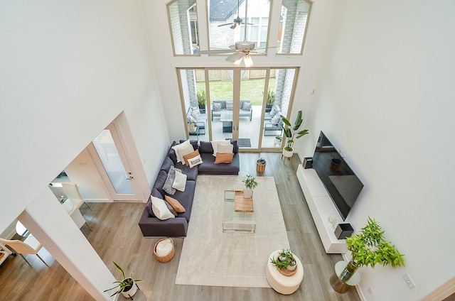 living room with a towering ceiling, ceiling fan, and wood finished floors