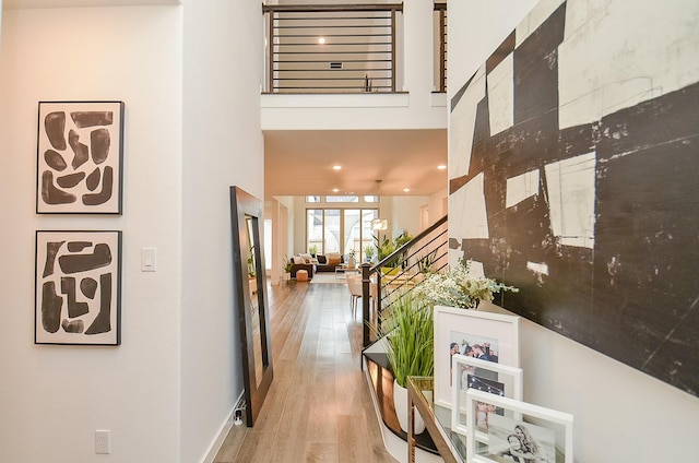 hallway with baseboards, a high ceiling, and wood finished floors